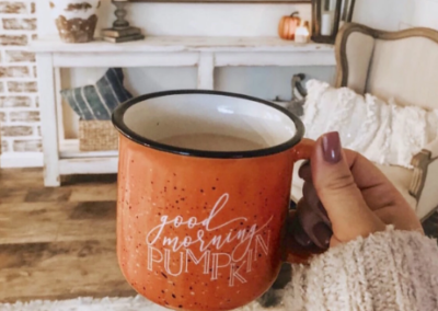 Woman holding orange mug with "Good Morning Pumpkin" written on it