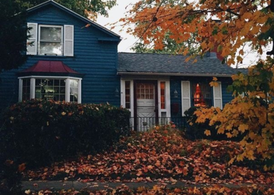 Blue house with fall leaves around it