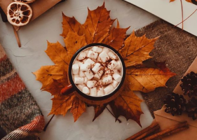 Overhead shot of fall drink with marshmallows resting on orange leaves
