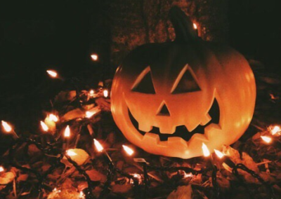Jack-o'-lantern on leaves with lights around it