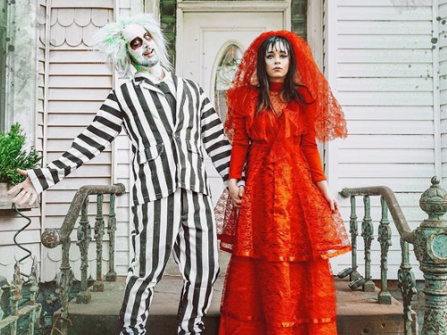 Two adults in Halloween costumes, one in Beetlejuice the other in red